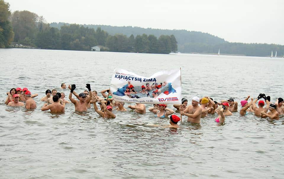 Morsy z Olsztyna w kąpieli zimowej na początku sezonu 2013/2014 nad jeziorem, z uczestnikami trzymającymi transparent.