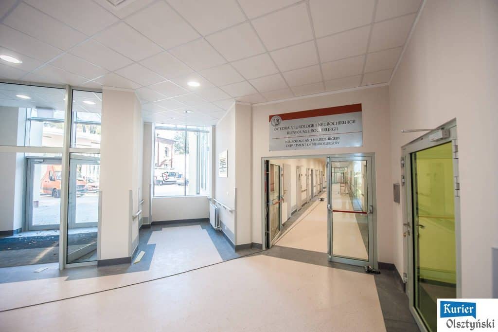Wnętrze korytarza szpitala z napisem "Katedra Neurologii i Neurochirurgii" na ścianie.