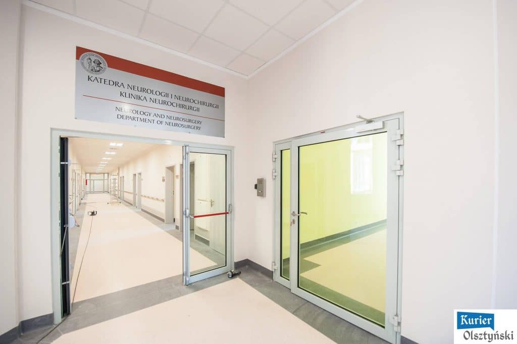 Wejście do nowego oddziału neurologii i neurochirurgii w szpitalu z tablicą informacyjną nad drzwiami.