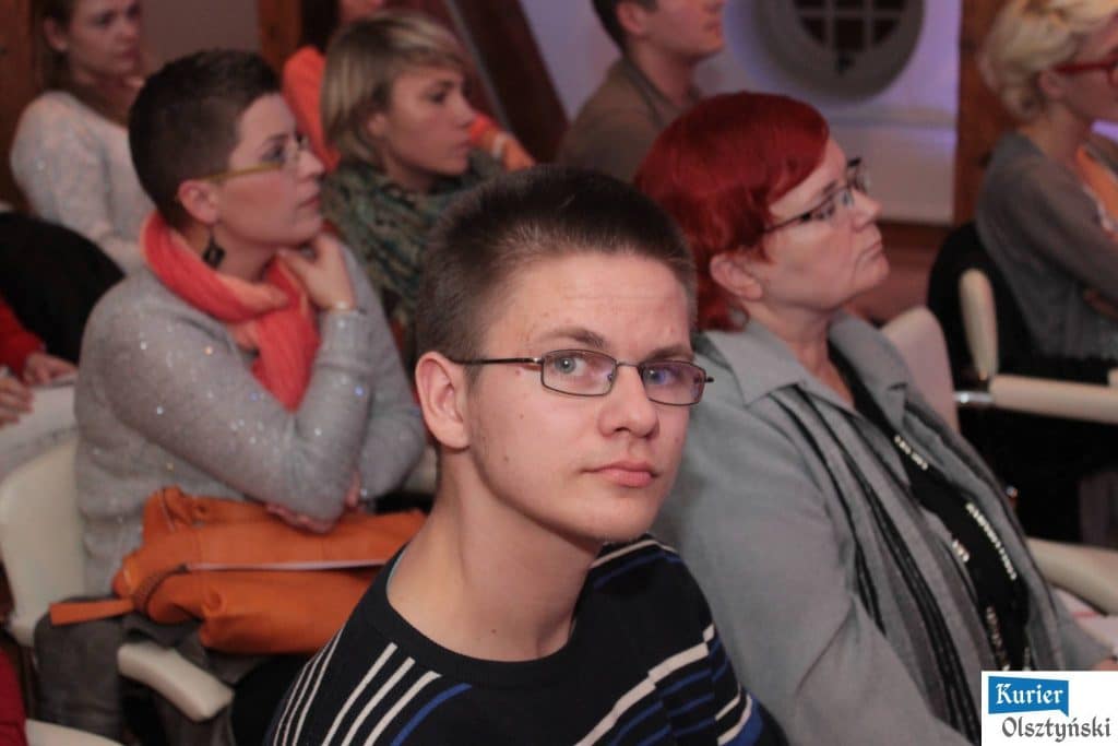 Grupa osób siedzących na widowni podczas finału slamu poetyckiego, widoczni głównie kobiety i młody mężczyzna na pierwszym planie.