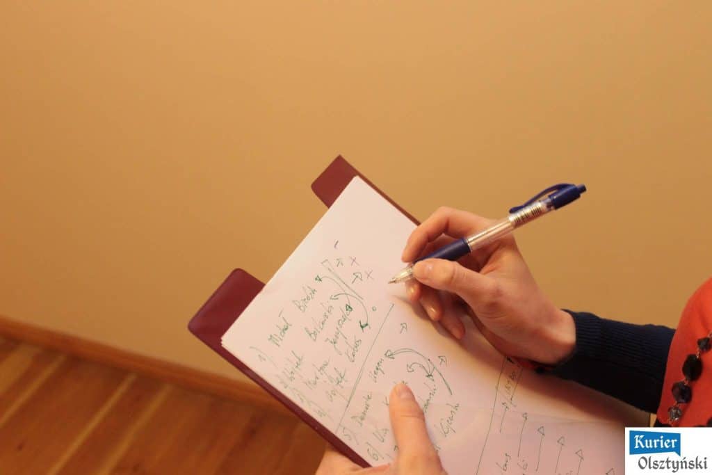 Osoba pisze na notesie z czaszkami, rysunkami i tekstami podczas wydarzenia.