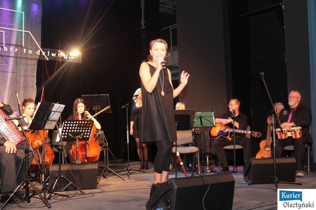 Muzycy na scenie podczas koncertu upamiętniającego Marka Grechutę, z wokalistką w centrum.