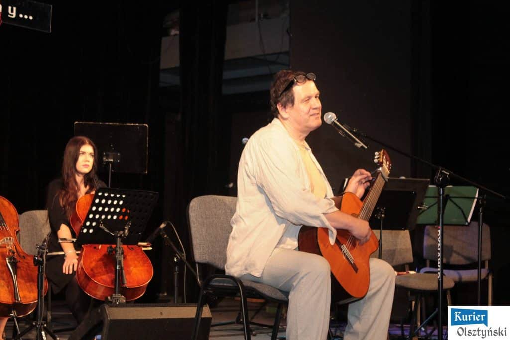 Muzyk grający na gitarze podczas koncertu upamiętniającego Marka Grechutę, w tle kobieta na gitarze.