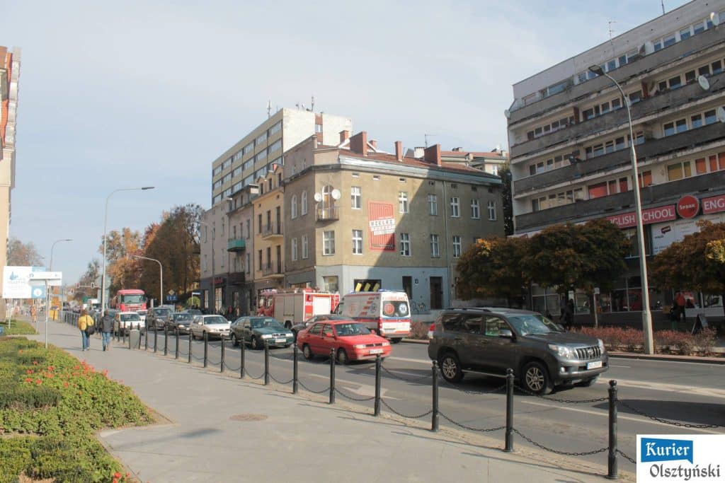 Akcja służb ratunkowych na ulicy Liszewskiego w centrum Olsztyna, widoczne pojazdy ratownicze i policja.