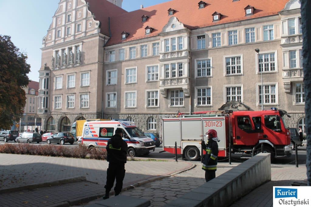 Widok akcji ratunkowej na ulicy Liszewskiego, w tle budynek ratusza, strażacy i ratownicy w akcji.