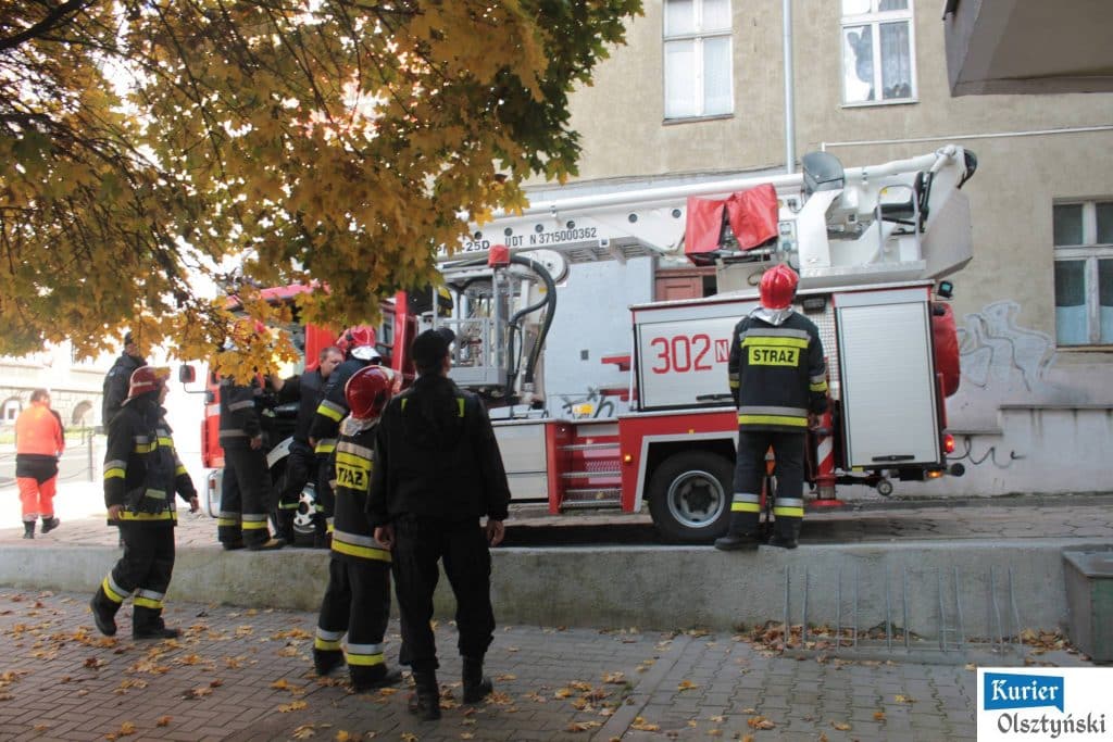 Strażacy i ratownicy na miejscu akcji przy budynku w centrum miasta, w pobliżu ratusza.
