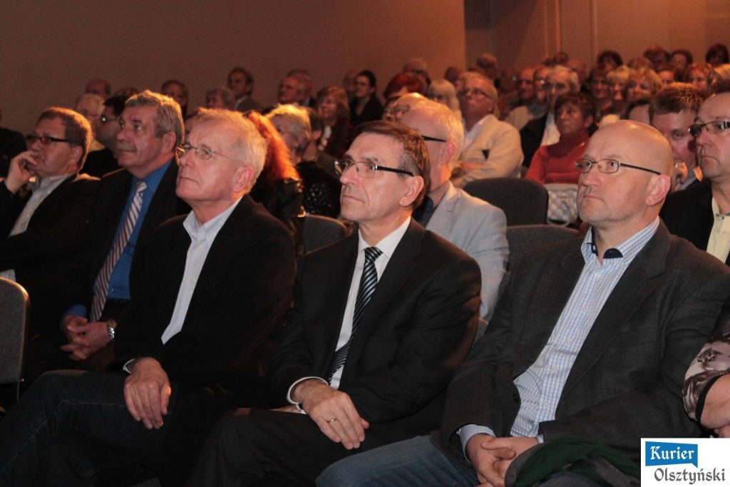 Uczestnicy wydarzenia siedzą na sali podczas projekcji filmu o Julianie Żołnierkiewiczu.