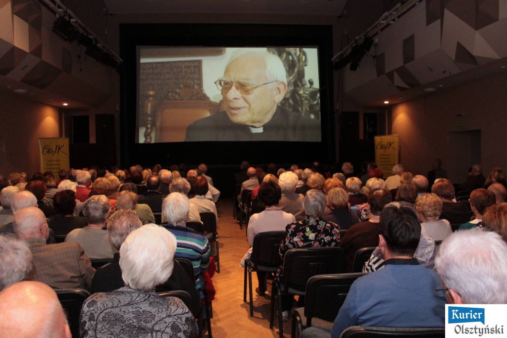 Widownia podczas projekcji filmu o księdzu Julianie Żołnierkiewiczu, wyświetlanym na dużym ekranie w centrum kultury.