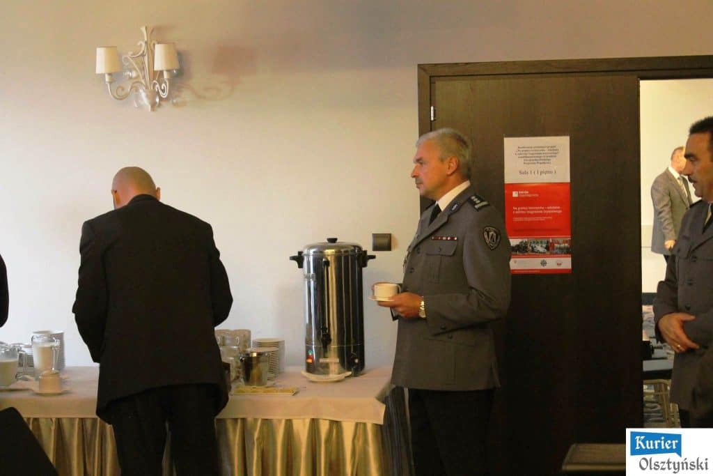 Mężczyzna w mundurze policyjnym stojąc przy bufecie podczas konferencji w hotelu.