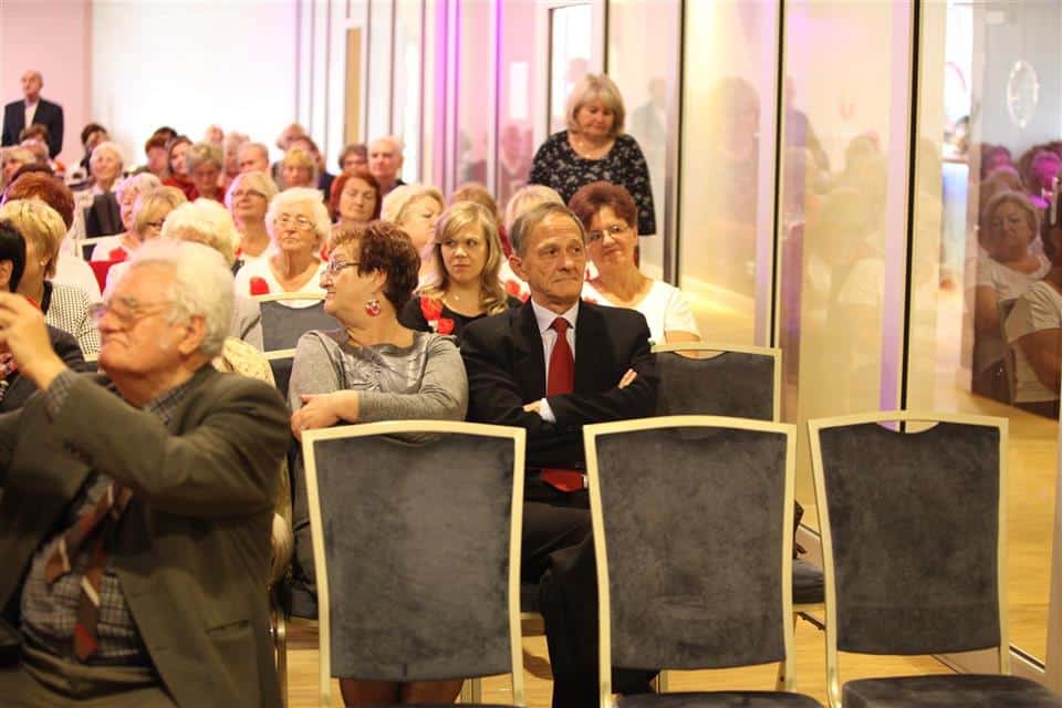 Grupa starszych słuchaczy siedzi na sali podczas inauguracji jubileuszu Akademii Trzeciego Wieku w Olsztynie.