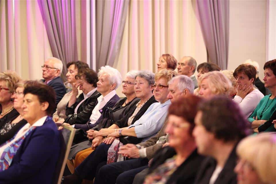 Uczestnicy uroczystości siedzą w sali konferencyjnej, słuchając wykładu i obchodząc jubileusz akademii.