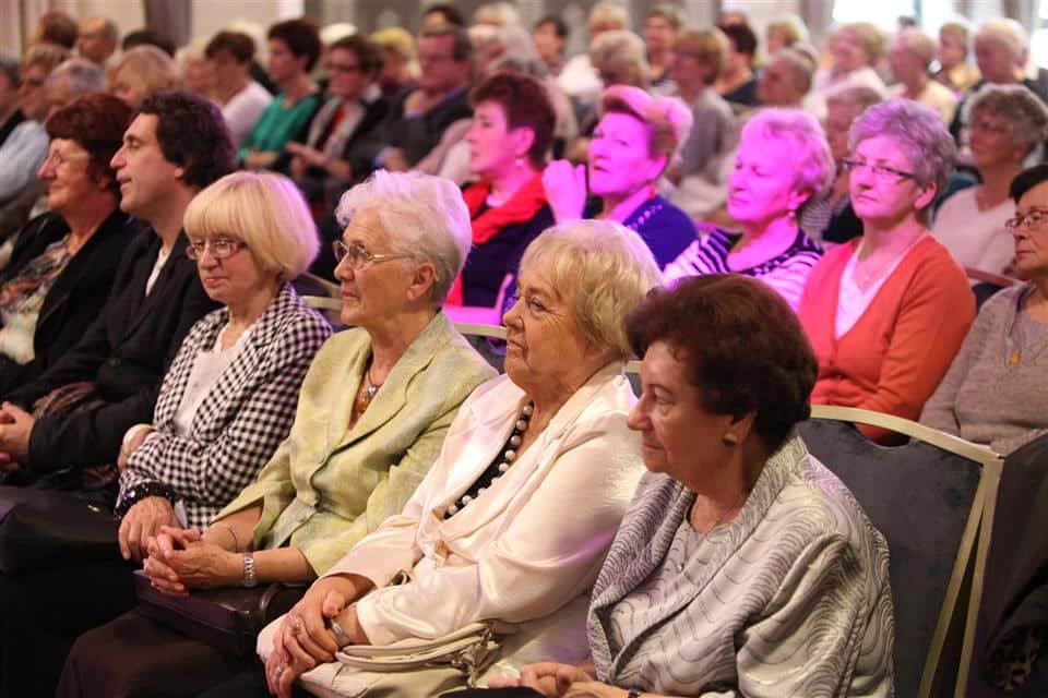 Grupa seniorek i seniorów siedzi na sali podczas uroczystości jubileuszowej Akademii Trzeciego Wieku.