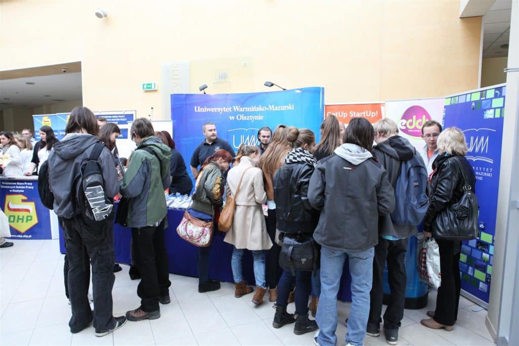 Tłum ludzi podczas targów pracy przy stoiskach uczelni i firm w Centrum Konferencyjno-Szkoleniowym uniwersytetu.