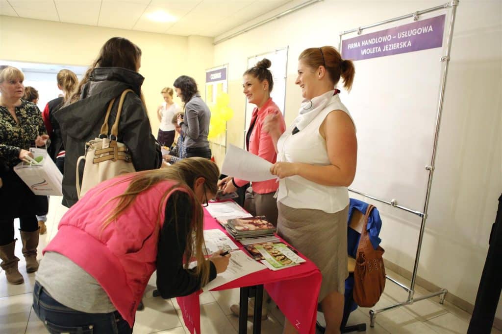 Stoiska i uczestnicy podczas targów pracy w Kortowie, rozmowy i rozdawanie materiałów informacyjnych.