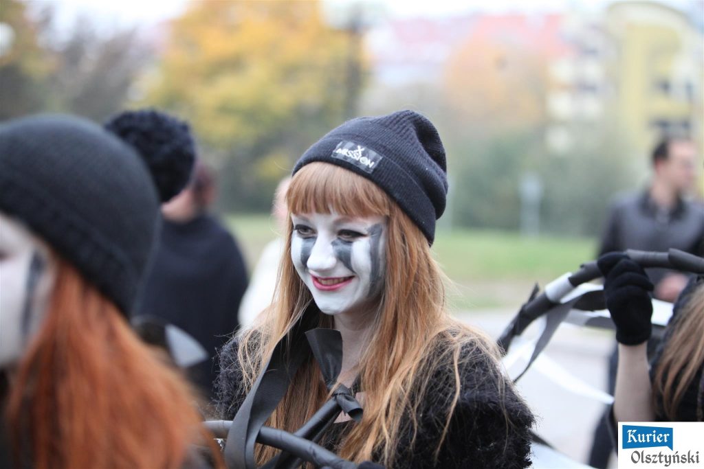 Młoda dziewczyna z pomalowaną twarzą na balu przebierańców, uśmiechająca się.