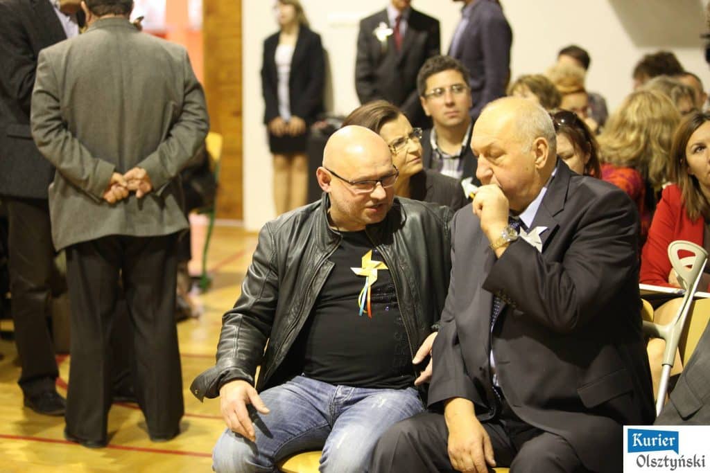 Uczestnicy uroczystości 25-lecia szkoły plastycznej w Olsztynie, rozmawiający i zaangażowani w wydarzenie.
