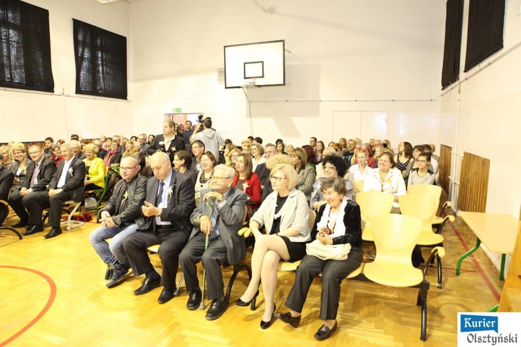 Sala okrągła pełna gości na uroczystości 25-lecia szkoły plastycznej, widoczne ławki i kosz