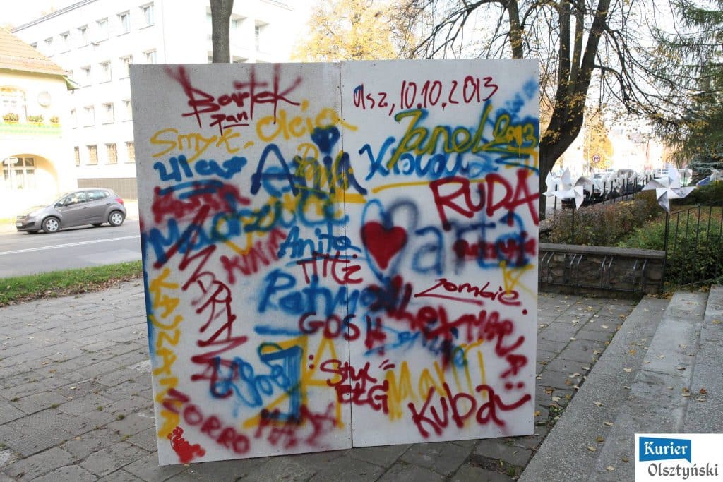Kolorowa graffiti na ścianie z datą 10.10.2013 i różnymi imionami.