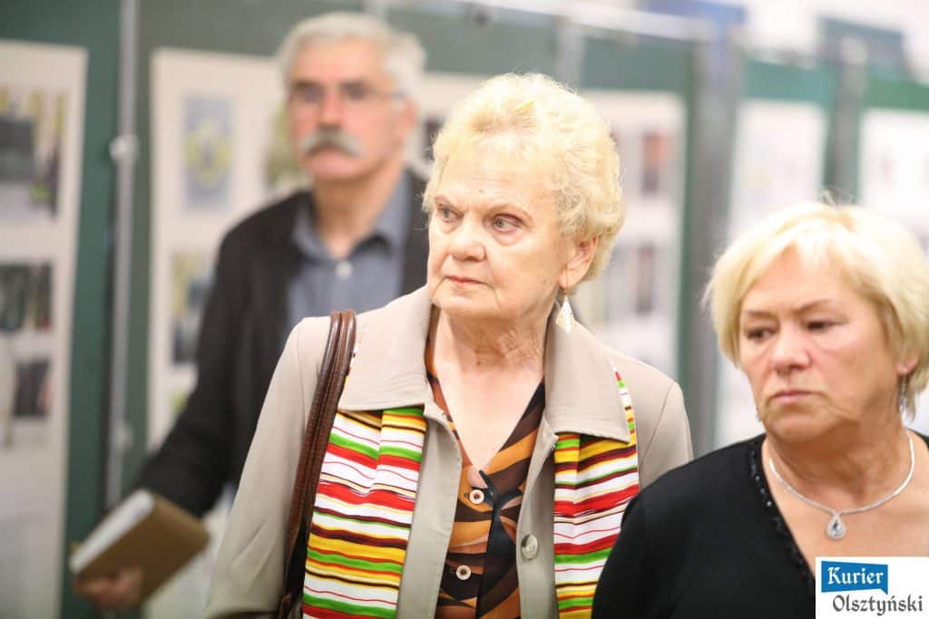 Widok na trzy kobiety i mężczyznę na wystawie zdjęć związanej z obchodami bitwy pod Lenino.