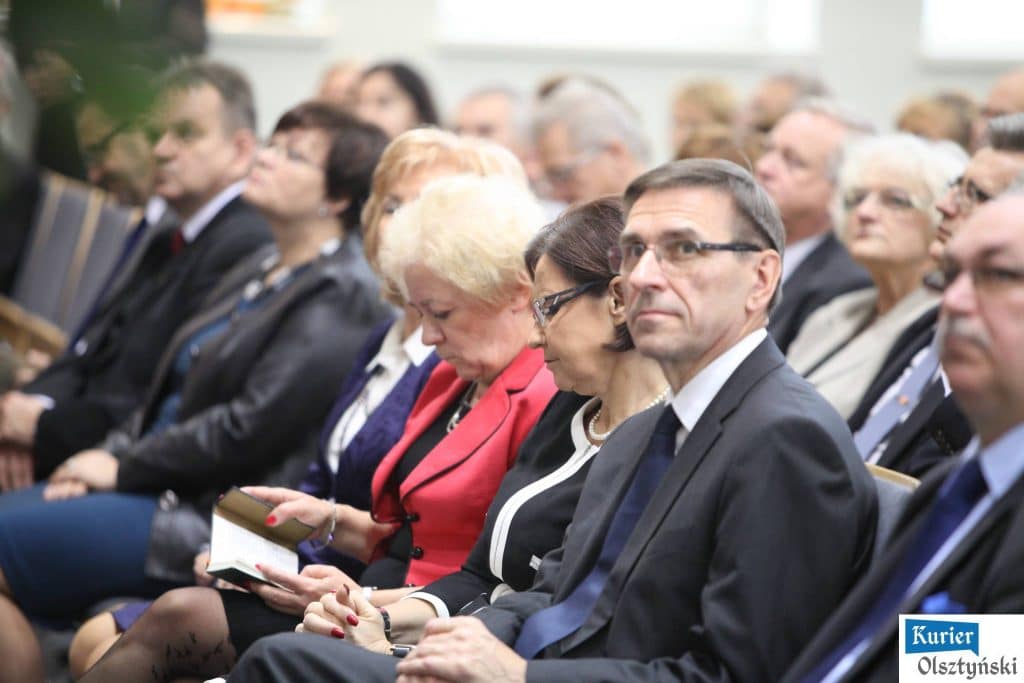 Uczestnicy oficjalnych obchodów Dnia Edukacji Narodowej w urzędzie, siedzący na sali konferencyjnej, w strojach formalnych.