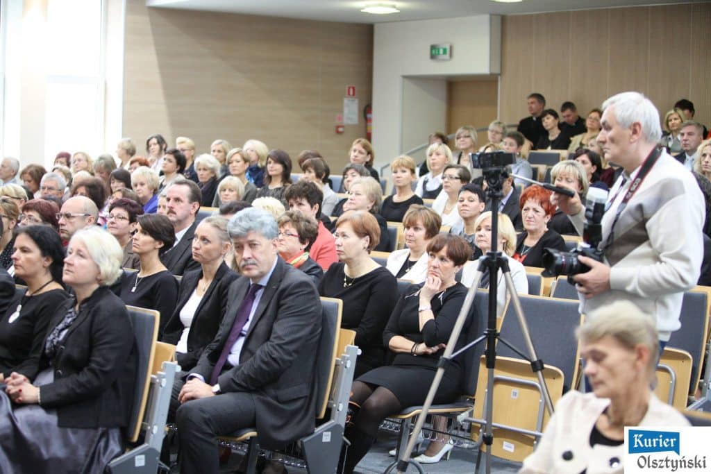 Uczestnicy uroczystości na sali podczas obchodów Dnia Edukacji Narodowej, z widokiem na pełne zasiedzenie widowni.