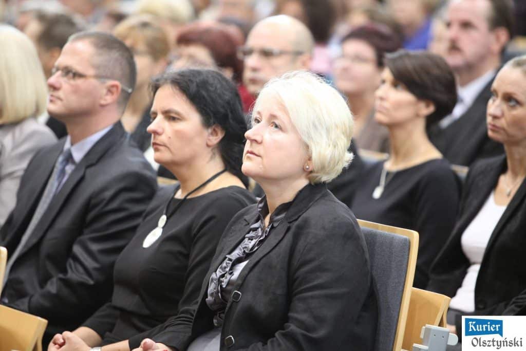 Grupa osób siedzi na oficjalnej uroczystości z okazji Dnia Edukacji Narodowej, większość w formalnych strojach.