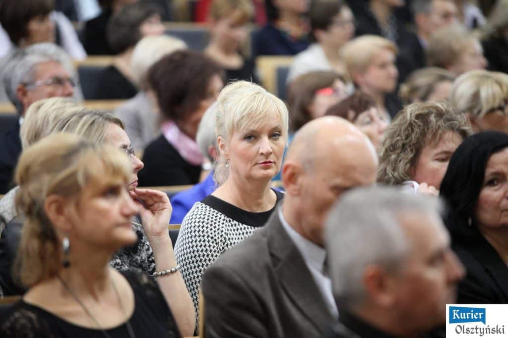 Uczestnicy oficjalnych obchodów Dnia Edukacji Narodowej w urzędzie, z główną uwagę skupioną na kobiecie z blond włosami w niebieskiej sukience.