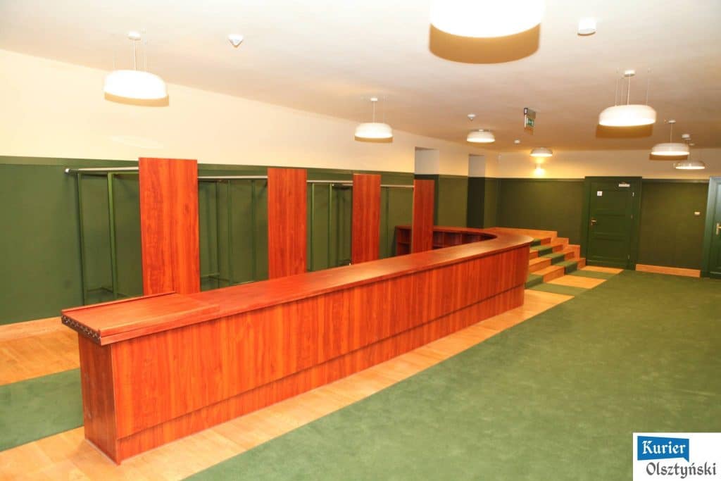 Nowo wyremontowane sale teatralne z drewnianym barkiem i zielonymi ścianami, puste i przygotowane do użytku.