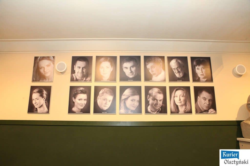 Zdjęcie sali teatralnej z czarno-białymi portretami aktorów na ścianie.