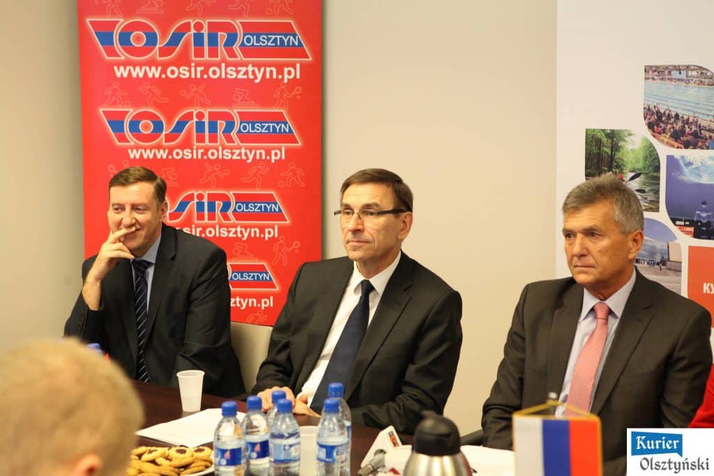 Grupa młodych pływaków z Polski i Rosji podczas mitingu w Aquasferze, obok plakatu informacyjnego.