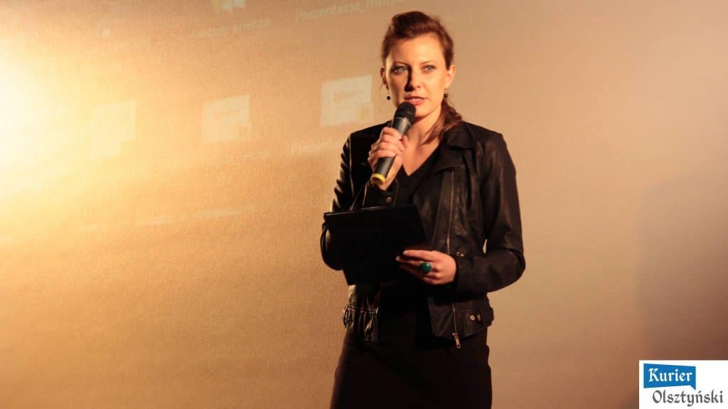 Magda Umer na scenie podczas inauguracji BabaFest w Olsztynie, trzyma mikrofon i notatnik.