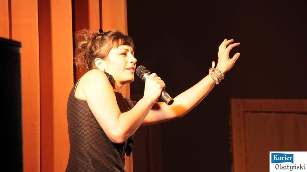 Magda Umer na scenie podczas inauguracji BabaFest, trzyma mikrofon i gestykuluje ręką.