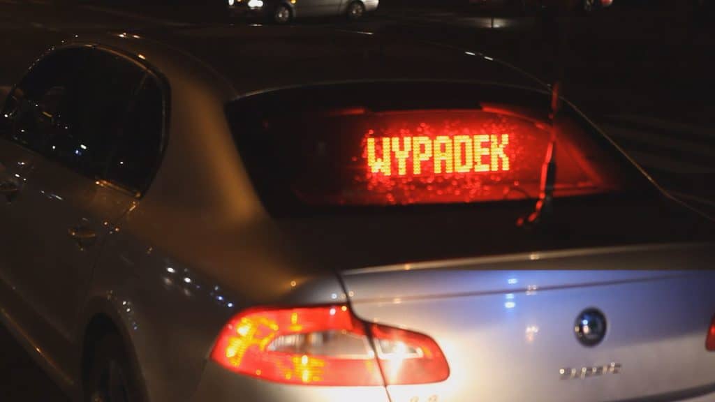 Samochód z wyświetlaczem 'Wypadek' na tylnej szybie, nocą na ulicy Sielskiej w Olsztynie.