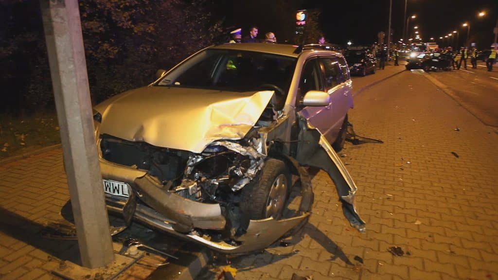 Rozbity samochód na chodniku obok słupa po kolizji na ulicy Sielskiej, z uszkodzeniami z przodu pojazdu.