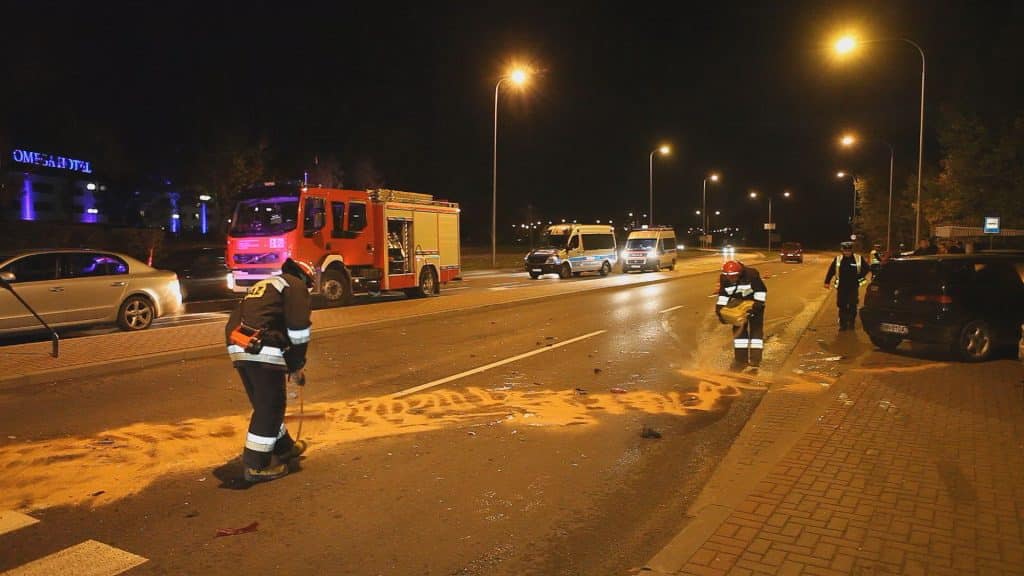 Straż pożarna i policja na miejscu kolizji na ulicy Sielskiej w Olsztynie, widoczny rozbity asfalt i zabezpieczone miejsce zdarzenia.