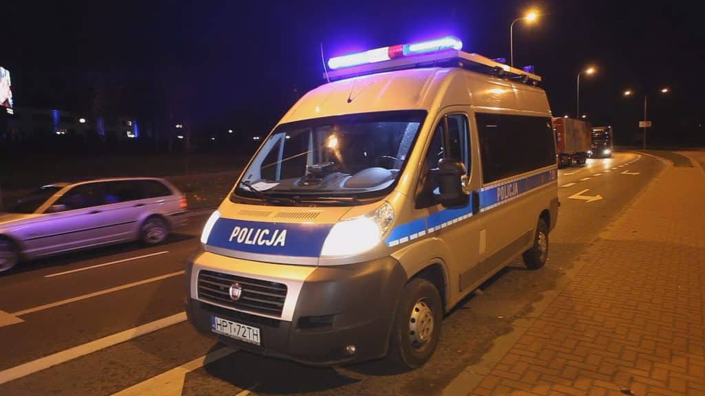 Policja na ulicy Sielskiej w nocy, na pierwszym planie samochód policyjny, w tle zatrzymane pojazdy i zablokowana droga.