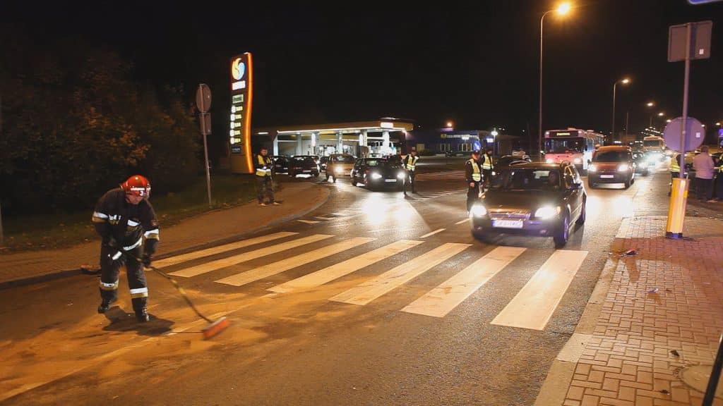 Widok na miejsce kolizji samochodów na ulicy Sielskiej w Olsztynie nocą, z policjantami i pracownikami na miejscu.