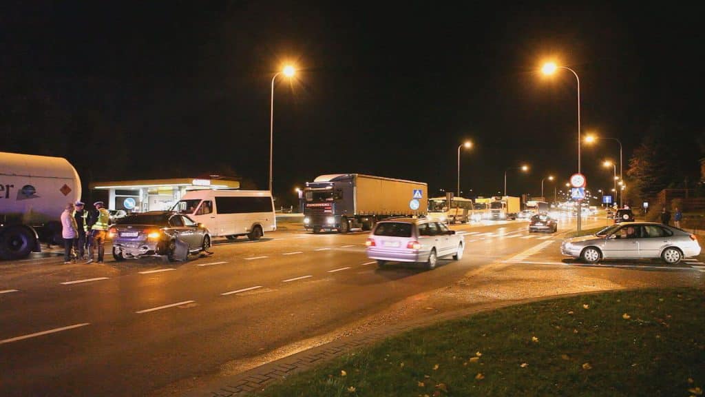 Kolizja czterech samochodów na głównej ulicy w Olsztynie w nocy, na zdjęciu widoczne słupy oświetleniowe i ruchliwa jezdnia.