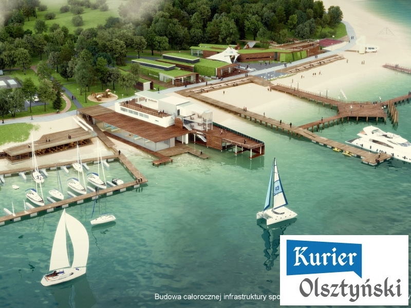 Widok na nowoczesną plażę miejską z pomostami, łodziami i zielonymi terenami w tle.
