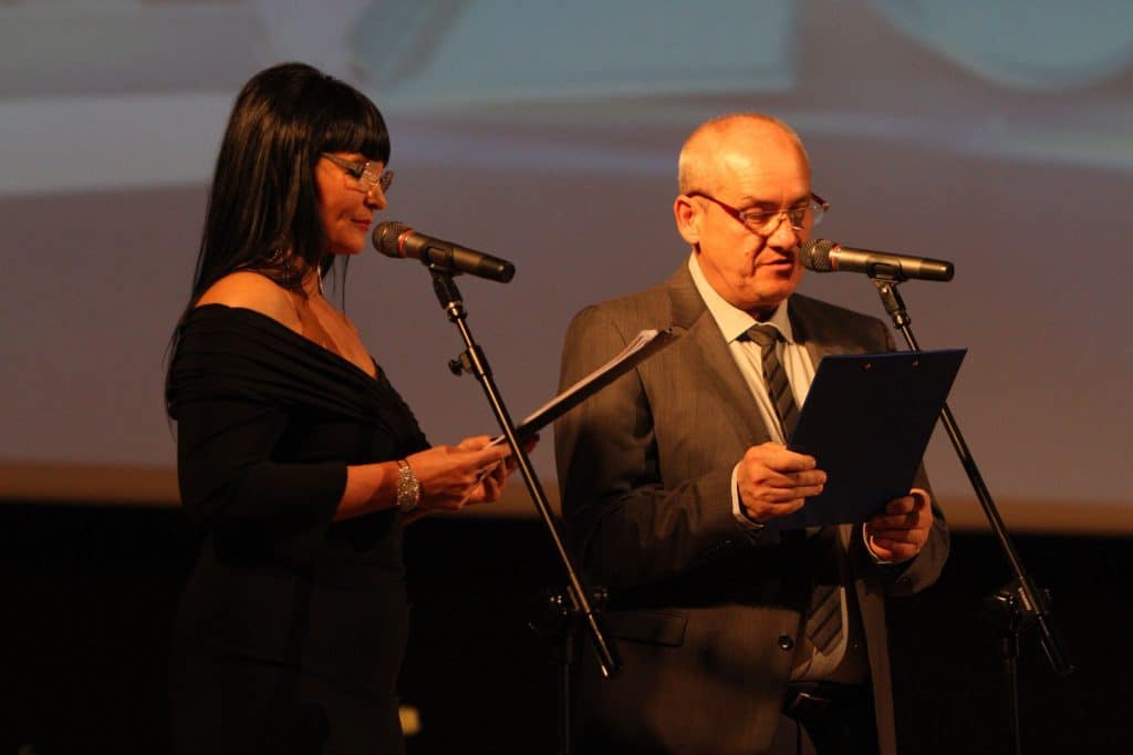 Dwoje osób na scenie podczas Gali Sportu 2014, kobieta i mężczyzna czytają z kart, w tle ekran projekcyjny.