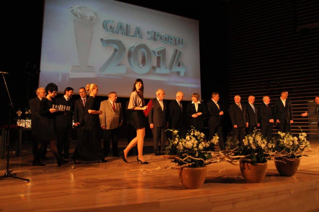 Grupa sportowców i urzędników na scenie podczas gali sportu w filharmonii, z dużym ekranem w tle wyświetlającym napis "GALA SPORTU 2014".