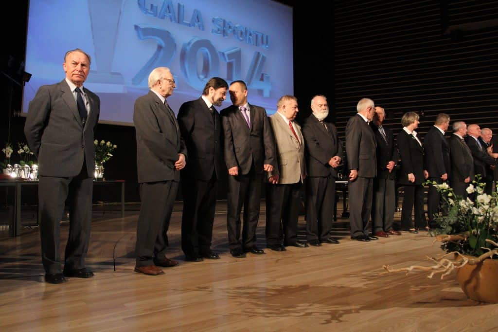 Grupa nagrodzonych sportowców i oficjeli na scenie podczas gali w filharmonii.