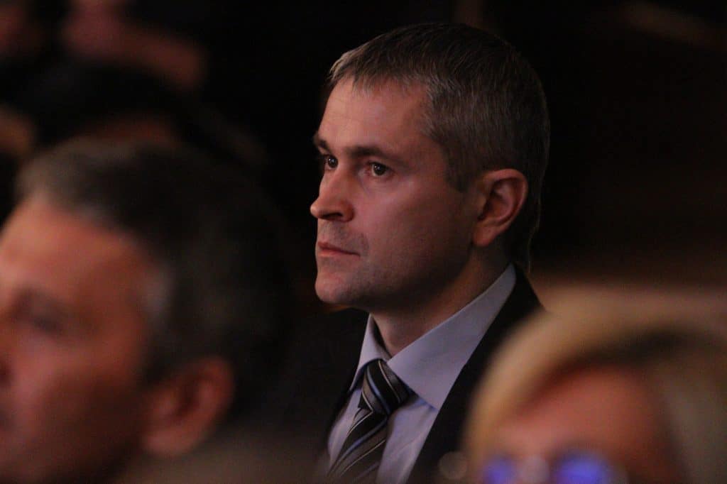 Mężczyzna w garniturze podczas gali w filharmonii, skupiony i poważny.