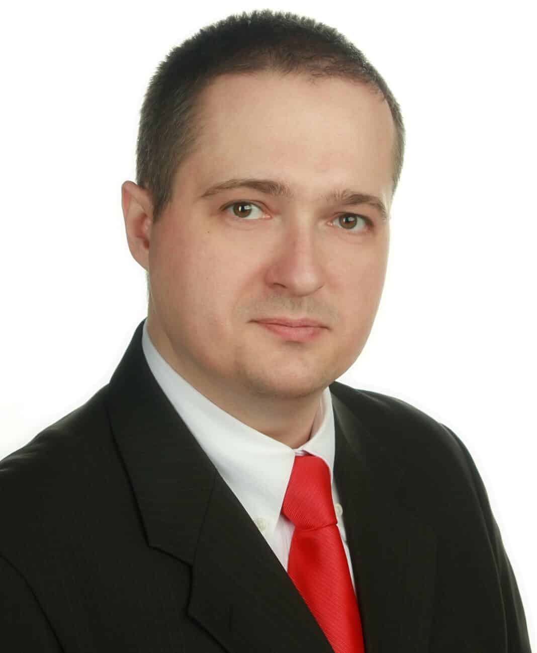 Michał Bagiński w garniturze, omawia psychoterapię online.