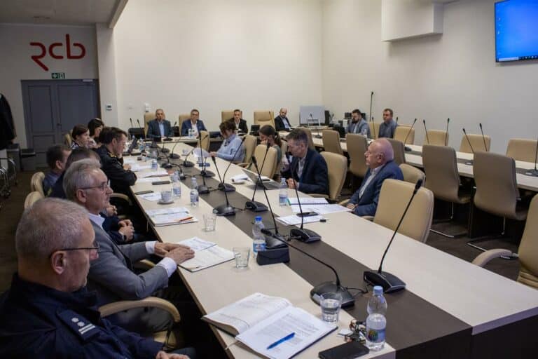 Uczestnicy spotkania zarządzania kryzysowego w sali konferencyjnej, omawiający przygotowania do zimy.