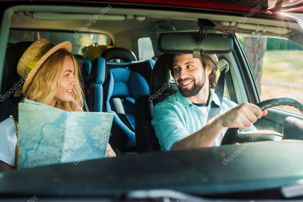 happy couple traveling by car with map