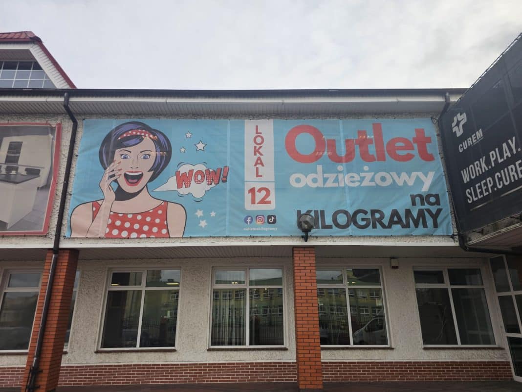 Baner reklamowy Outletu Odzieżowego z hasłem o odzieży na kilogramy.