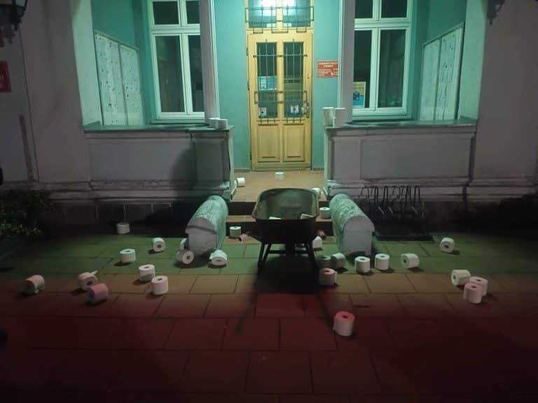 Taczka pełna papieru toaletowego przed urzędem miejskim w Dobrym Mieście