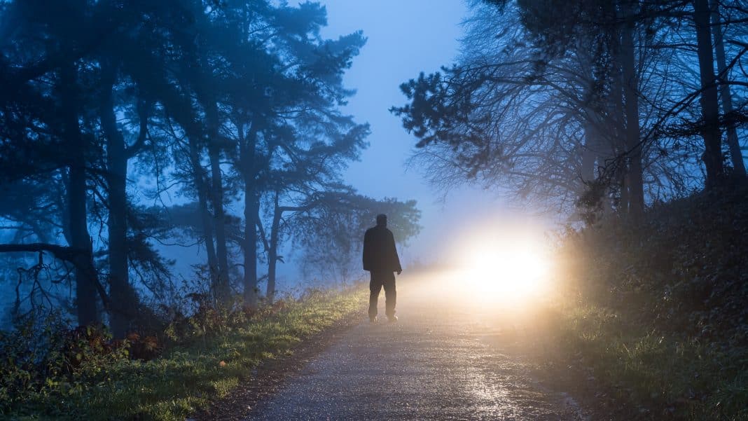 A mysterious moody photo of a a man silhouetted against car head