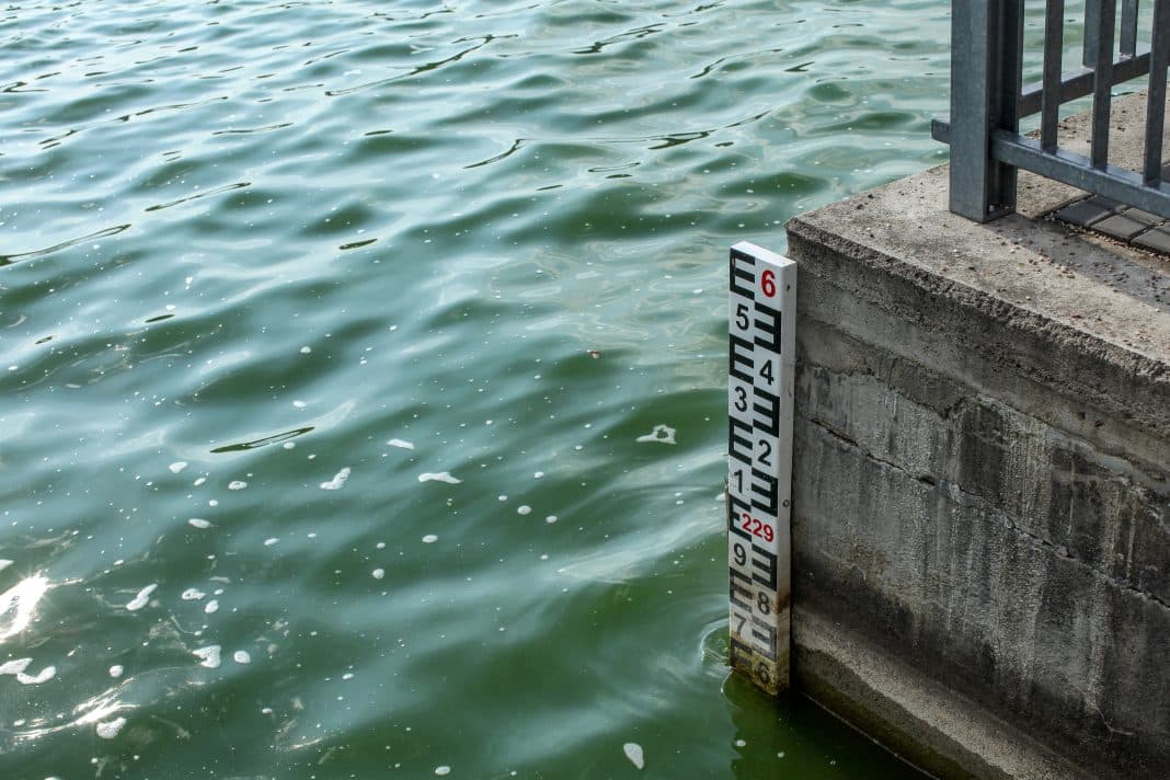 Water level indicator in green blue water at dam.